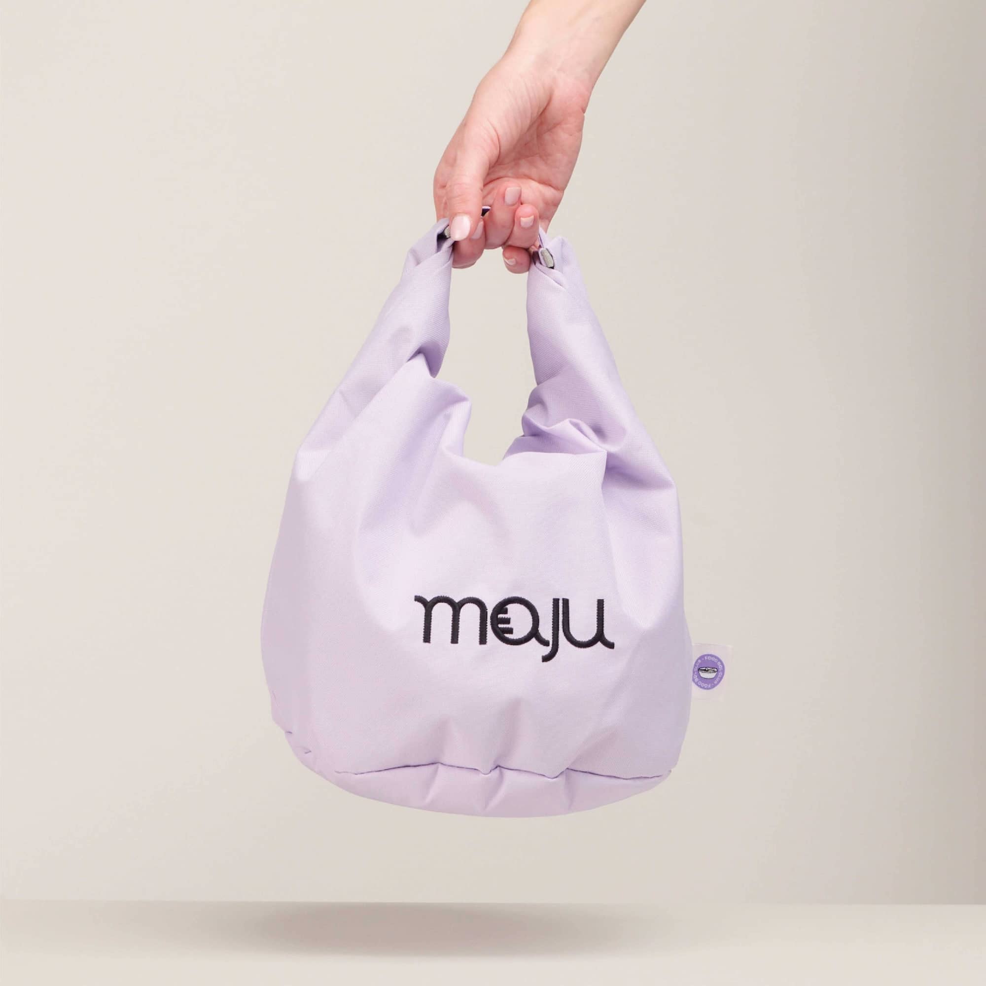 Sac isotherme maju de couleur violet maintenu par la main.